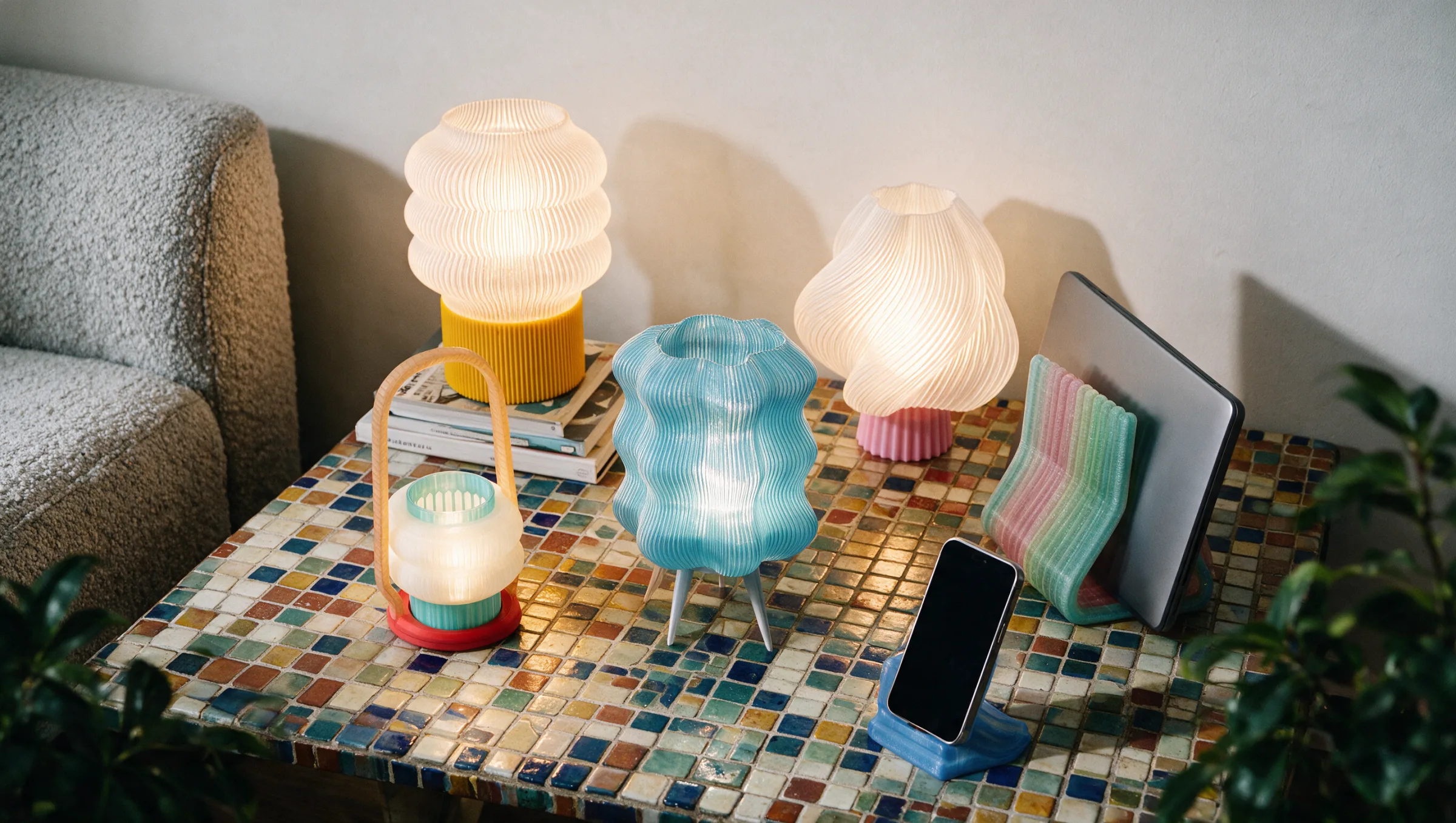 Lámparas encendidas, soportes para celular y tableta y una REEDD aqua sobre una mesa de mosaico